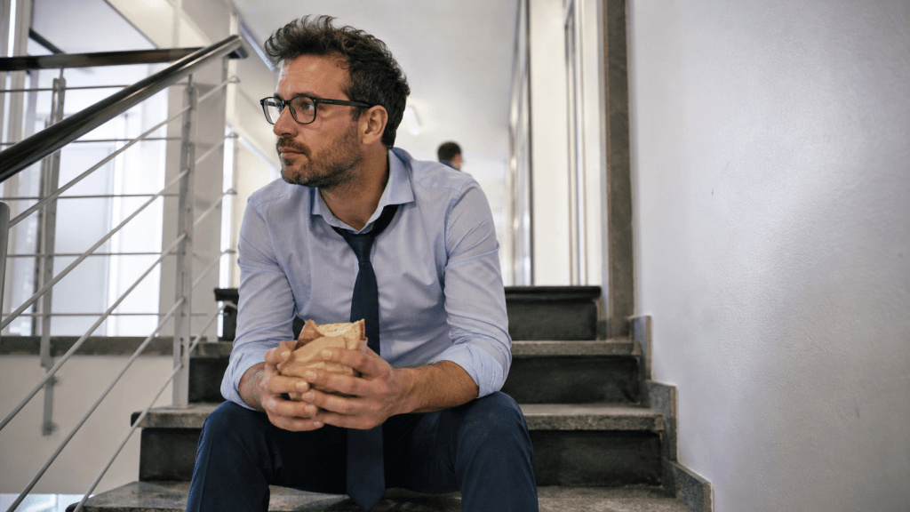 Mann macht eine kurze Pause mit Sandwich im Büro