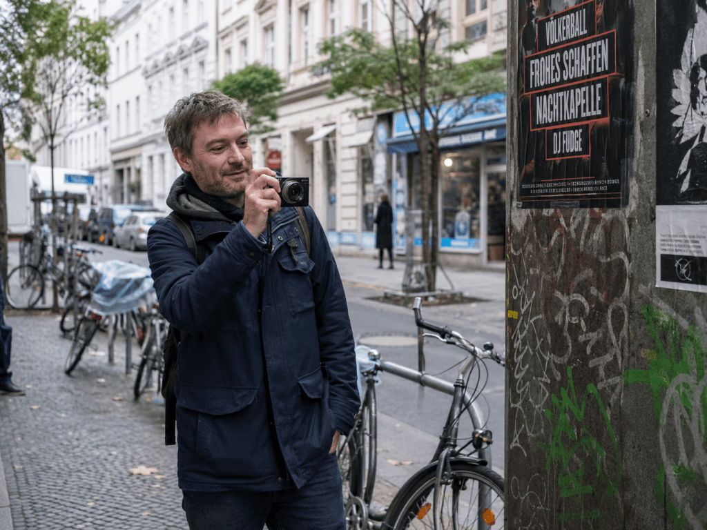 Mann fotografiert mit einer kleinen Kamera eine gewöhnliche Straßenszene in Deutschland