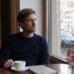 Mann im Café mit Notizbuch bei Gedanken zum Jahreswechsel und stiller Reflexion