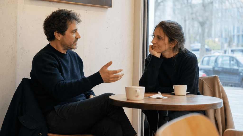 Mann und Frau unterhalten sich an einem kleinen Café-Tisch
