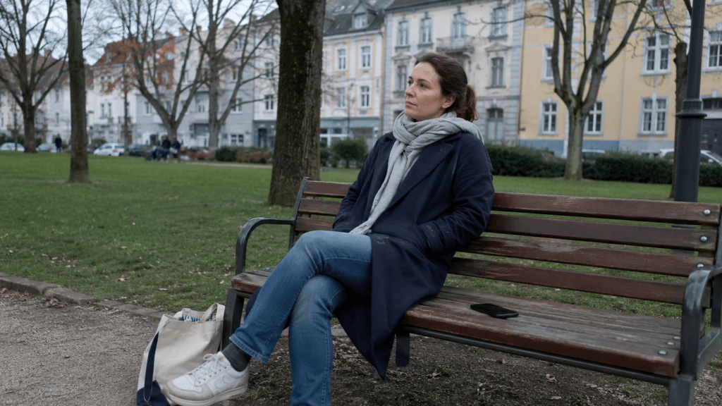 Frau sitzt im Park und macht eine bewusste kleine Pause
