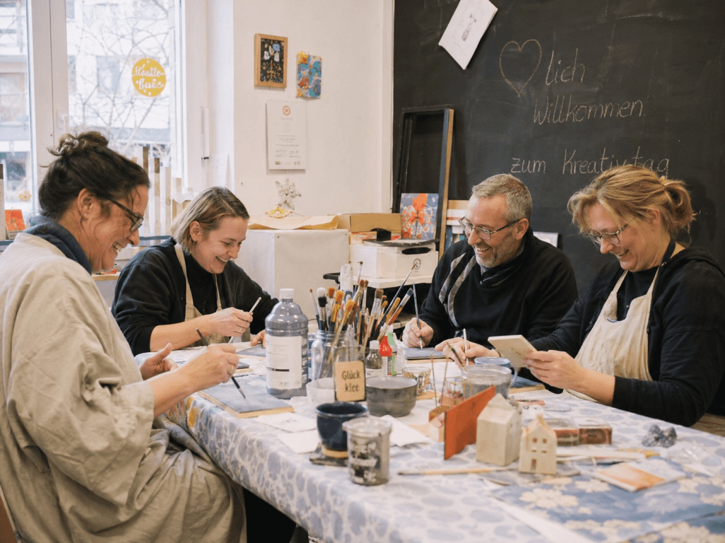 Erwachsene sitzen in einem Kreativ-Workshop zusammen und basteln in entspannter Atmosphäre