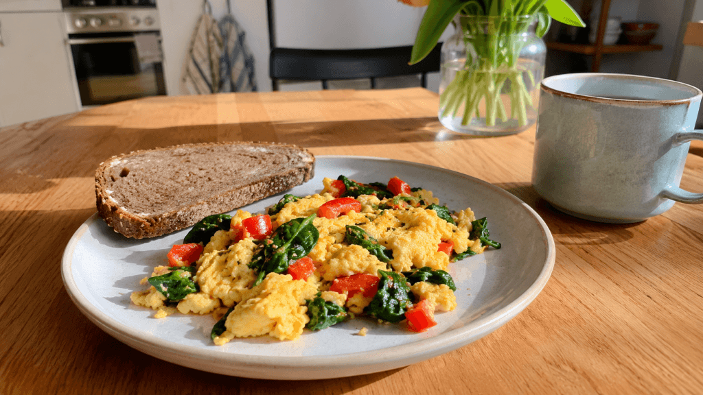 Leichtes Frühstück mit Rührei, Spinat, Paprika und Vollkornbrot