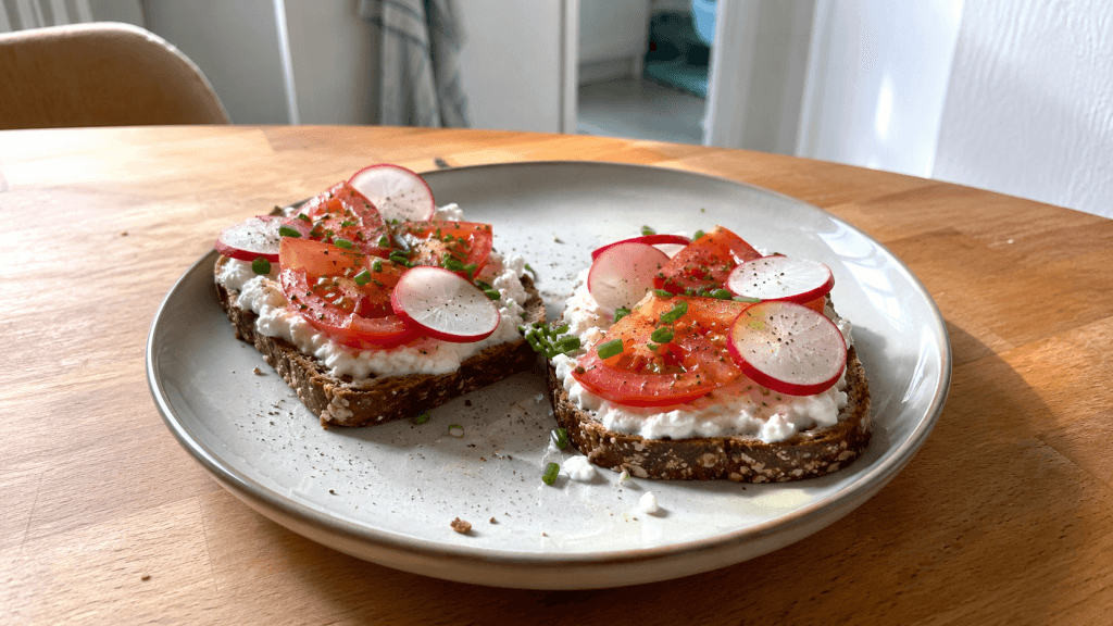 Zwei Scheiben Vollkornbrot mit Hüttenkäse, Tomaten und Radieschen