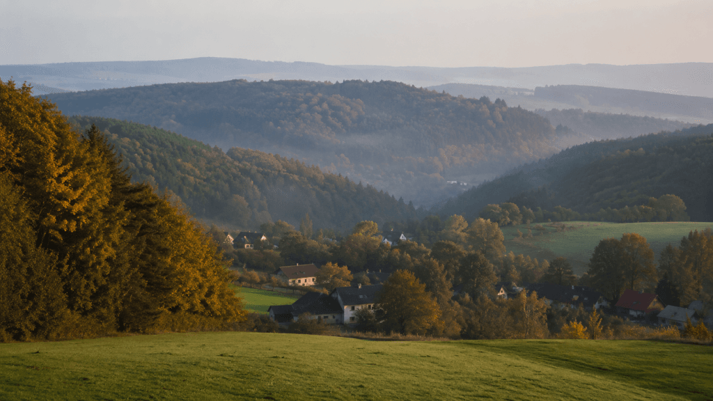 Odenwald-Landschaft mit bewaldeten Huegeln, Wiesen und Dorf im Tal