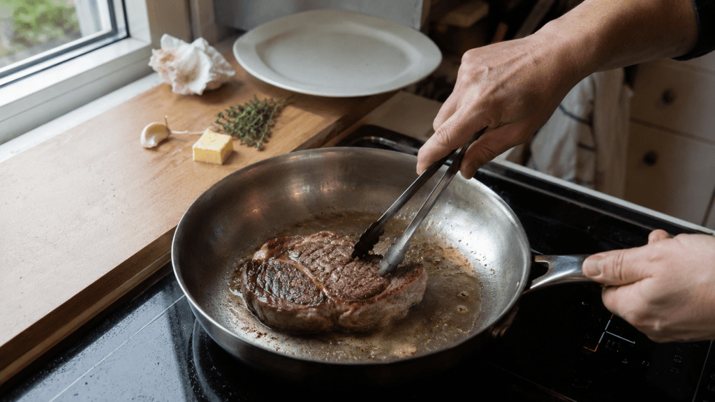 Kleines Rib-Eye-Steak brät in einer Pfanne mit etwas Öl