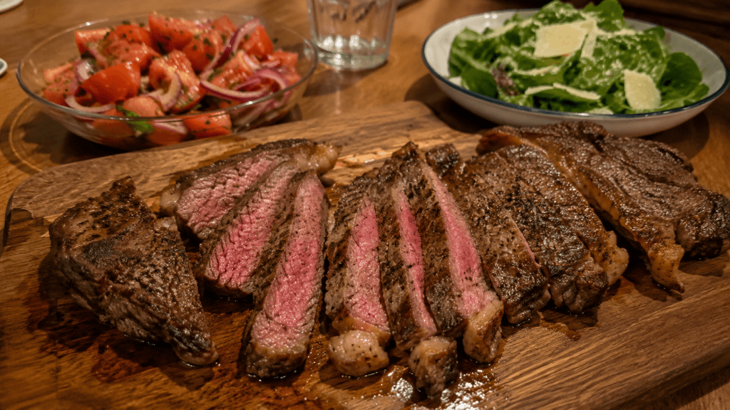 Rib-Eye-Steak mit Salat servieren, dazu Tomaten-Zwiebel-Salat und grüner Salat