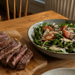 Rucola-Parmesan-Salat in einer Keramikschüssel neben geschnittenem Steak