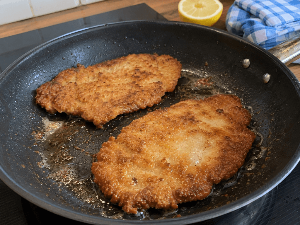 Schweinerücken Schnitzel in der Pfanne nach dem Braten mit Butter und Zitrone