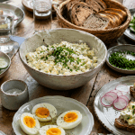 Eiersalat mit Skyr Rezept als proteinreicher Brunch für mehrere Personen mit Brotkorb, Eierhälften, Gurken, Radieschen und Schnittlauch.