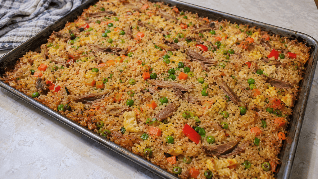 Gebackener Reis mit Ente aus dem Ofen mit Erbsen, Karotten, Paprika und Ei auf dem Blech