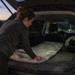 Frau bereitet im Auto einen Schlafplatz für eine sichere Pause unterwegs vor
