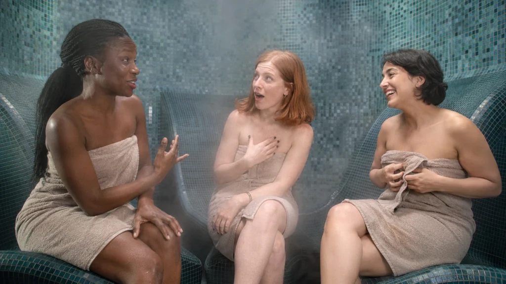 Drei Frauen lachen und erzählen sich etwas im Dampfbad